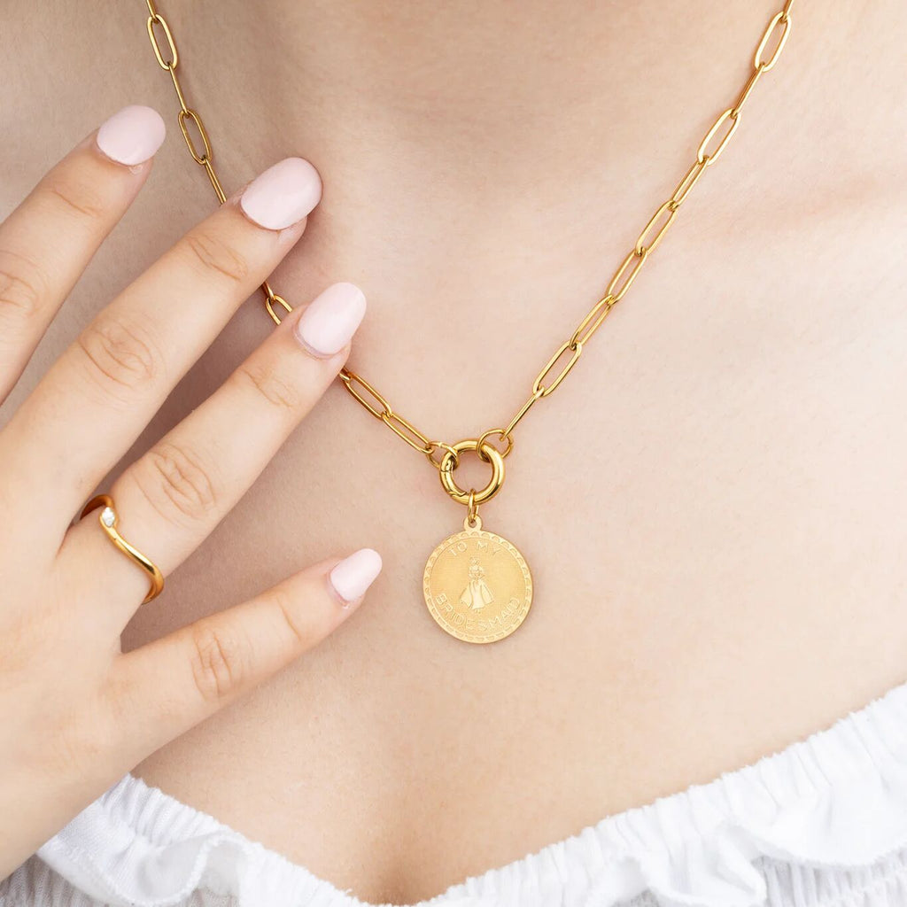 Gold necklace with a pendant worn by a person, close-up on a neutral background