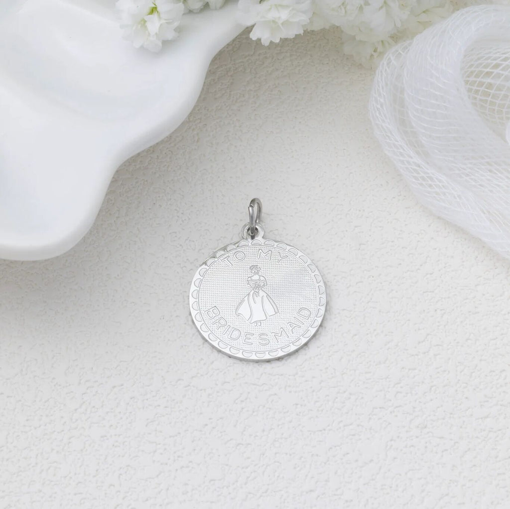 Silver pendant on a light gray surface with white flowers in the background