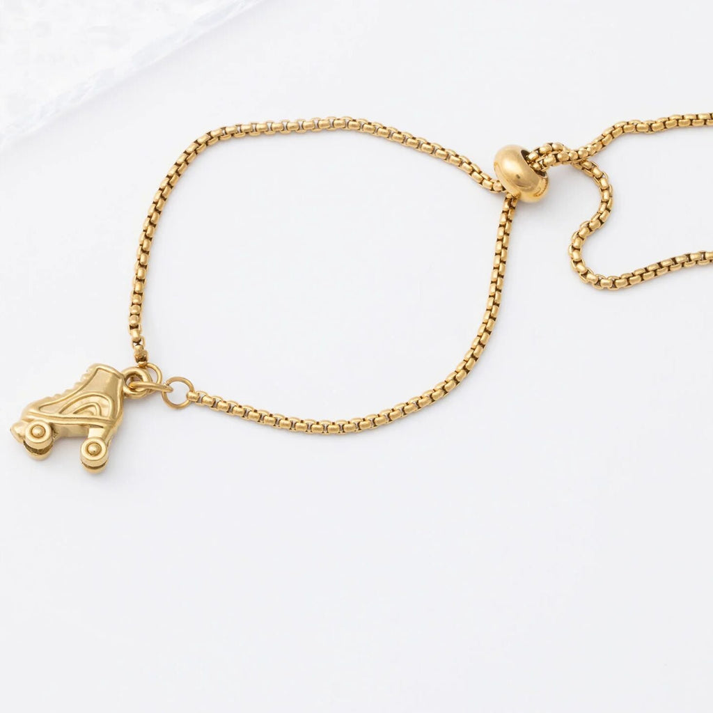 Gold bracelet with a roller skate charm on a white background