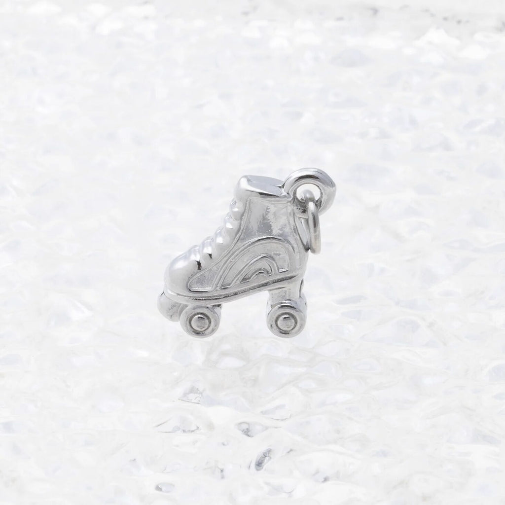 Silver roller skate charm on a white marble background