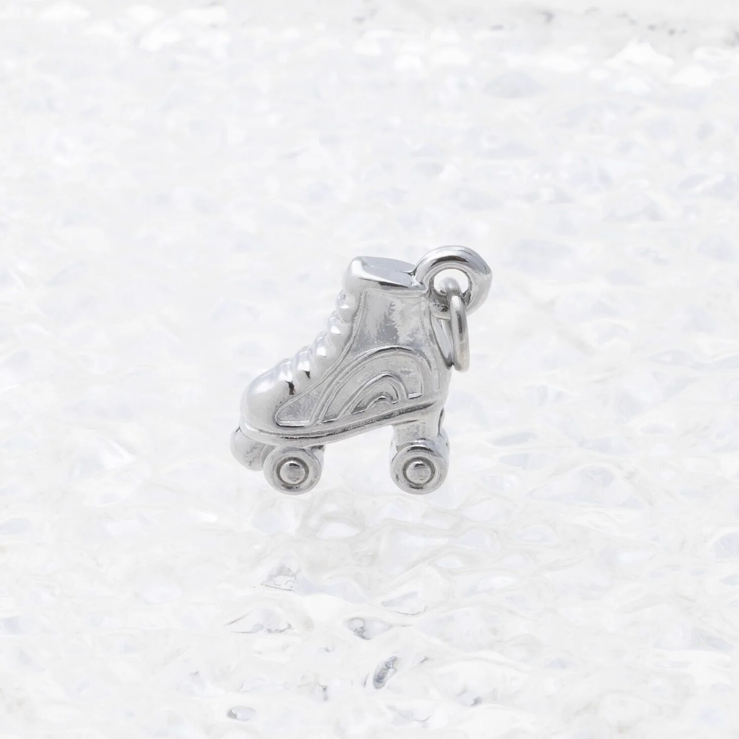 Silver roller skate charm on a white marble background