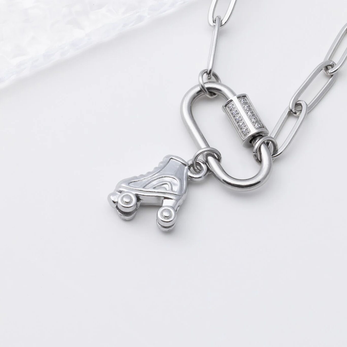 Silver necklace with a roller skate charm on a white background
