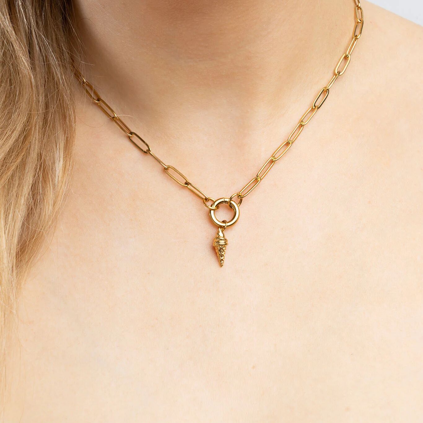 Gold chain necklace with an ice cream pendant on a person's neck
