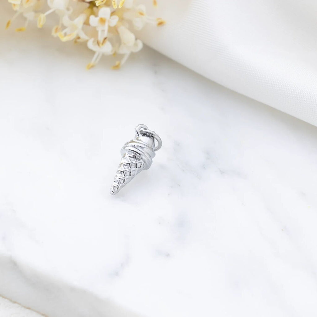 Silver charm resembling an ice cream cone on a white background with flowers.