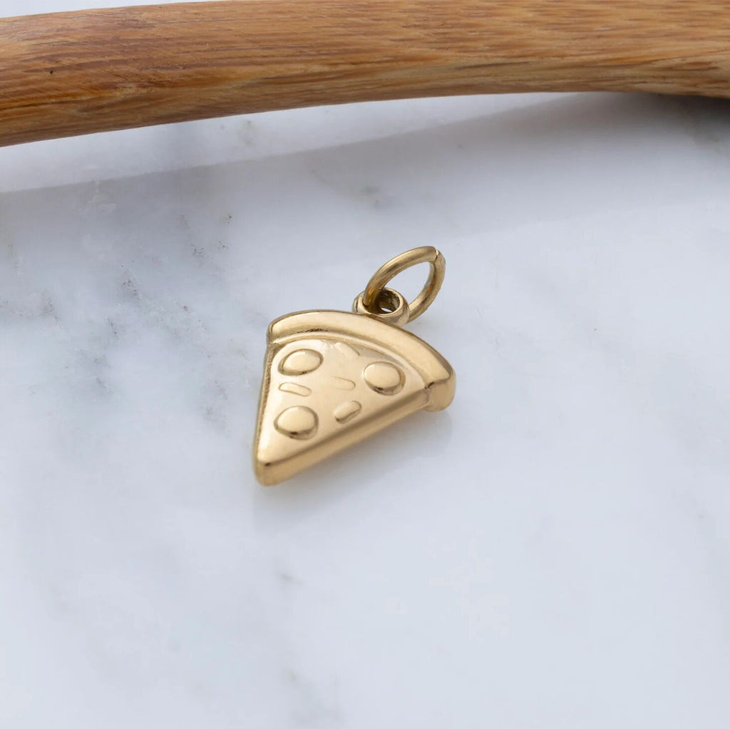 Gold pizza slice pendant on a marble surface with a wooden stick in the background