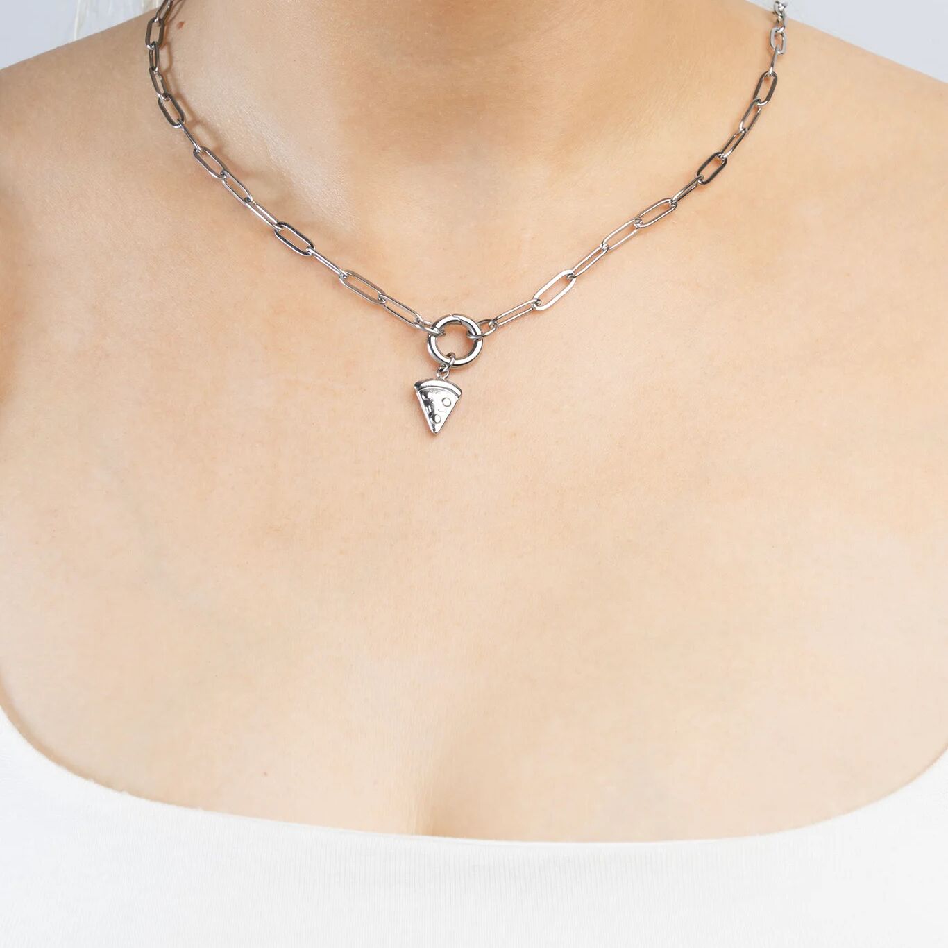 Silver necklace with a pizza shaped pendant on a plain background