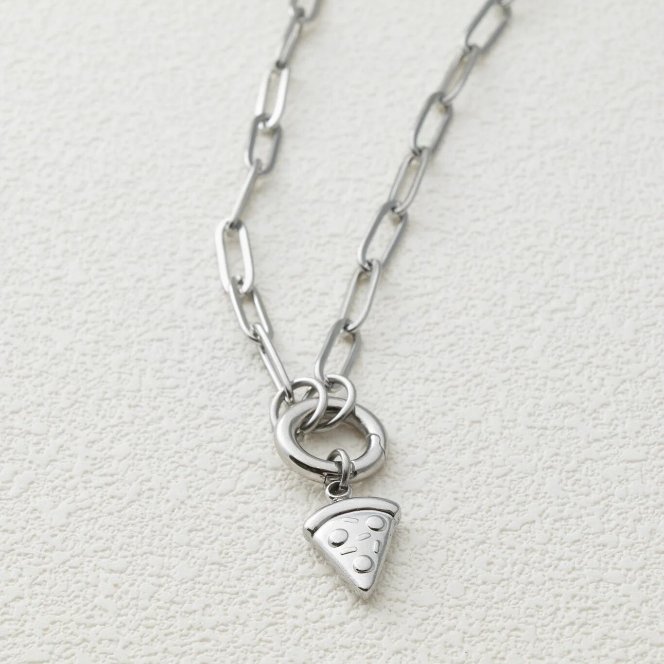 Silver necklace with a pizza slice charm on a light gray background