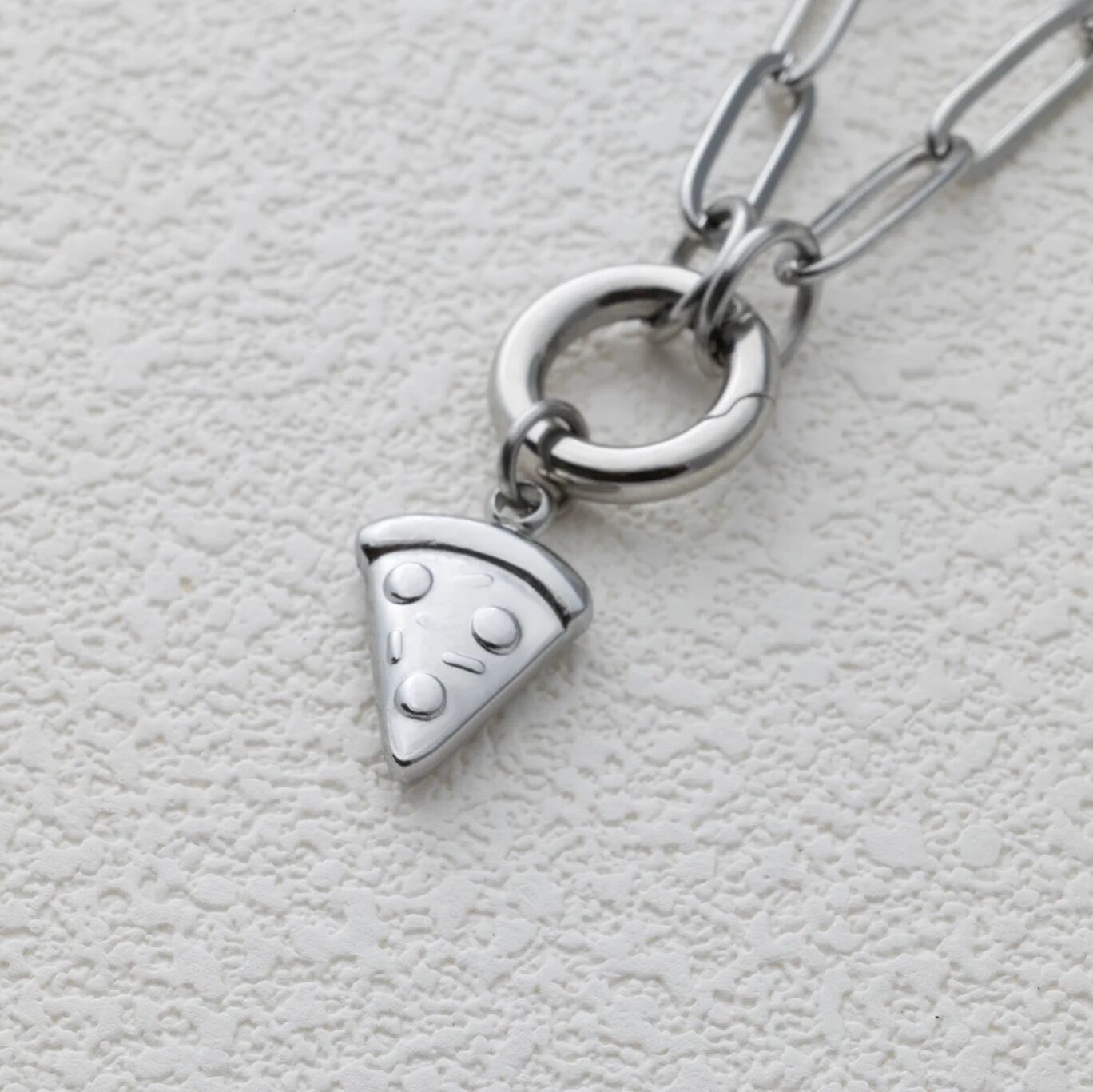 Silver necklace with a pizza slice charm on a light gray background