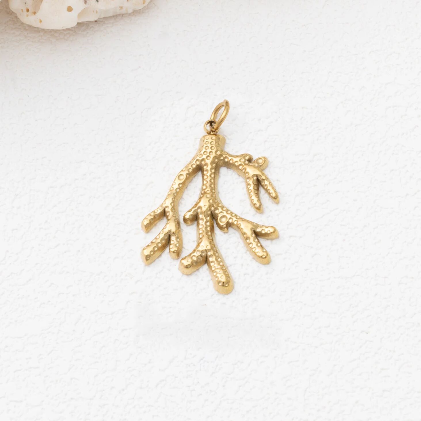 Gold coral pendant on a white background