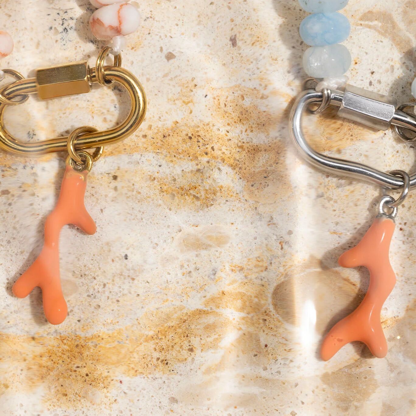 Two necklaces with coral charms on a textured surface