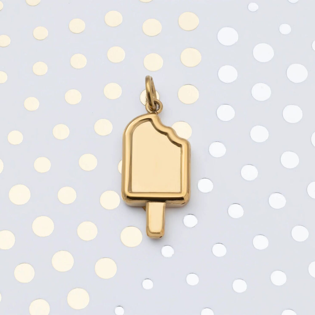 Gold popsicle charm on a polka dot background