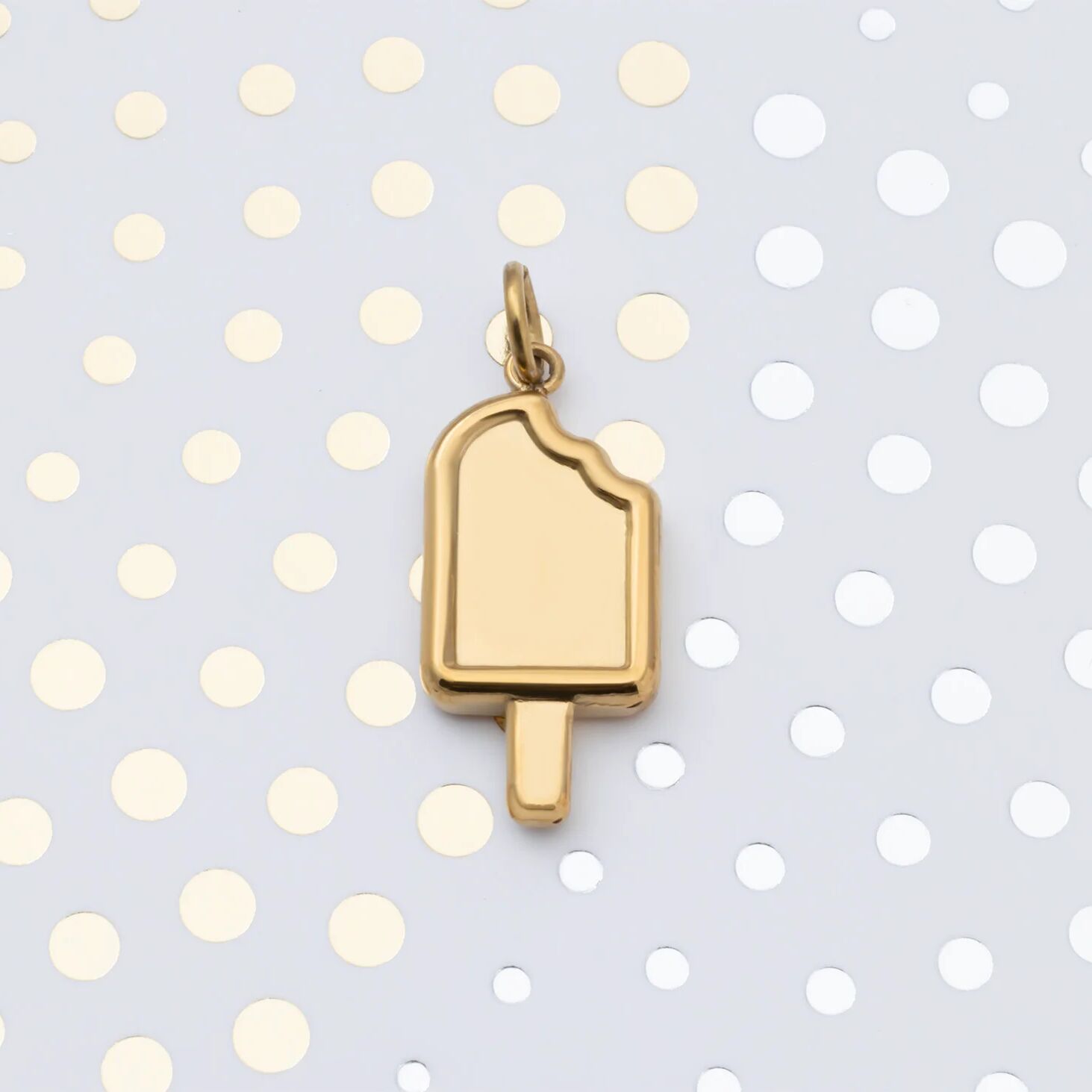 Gold popsicle charm on a polka dot background