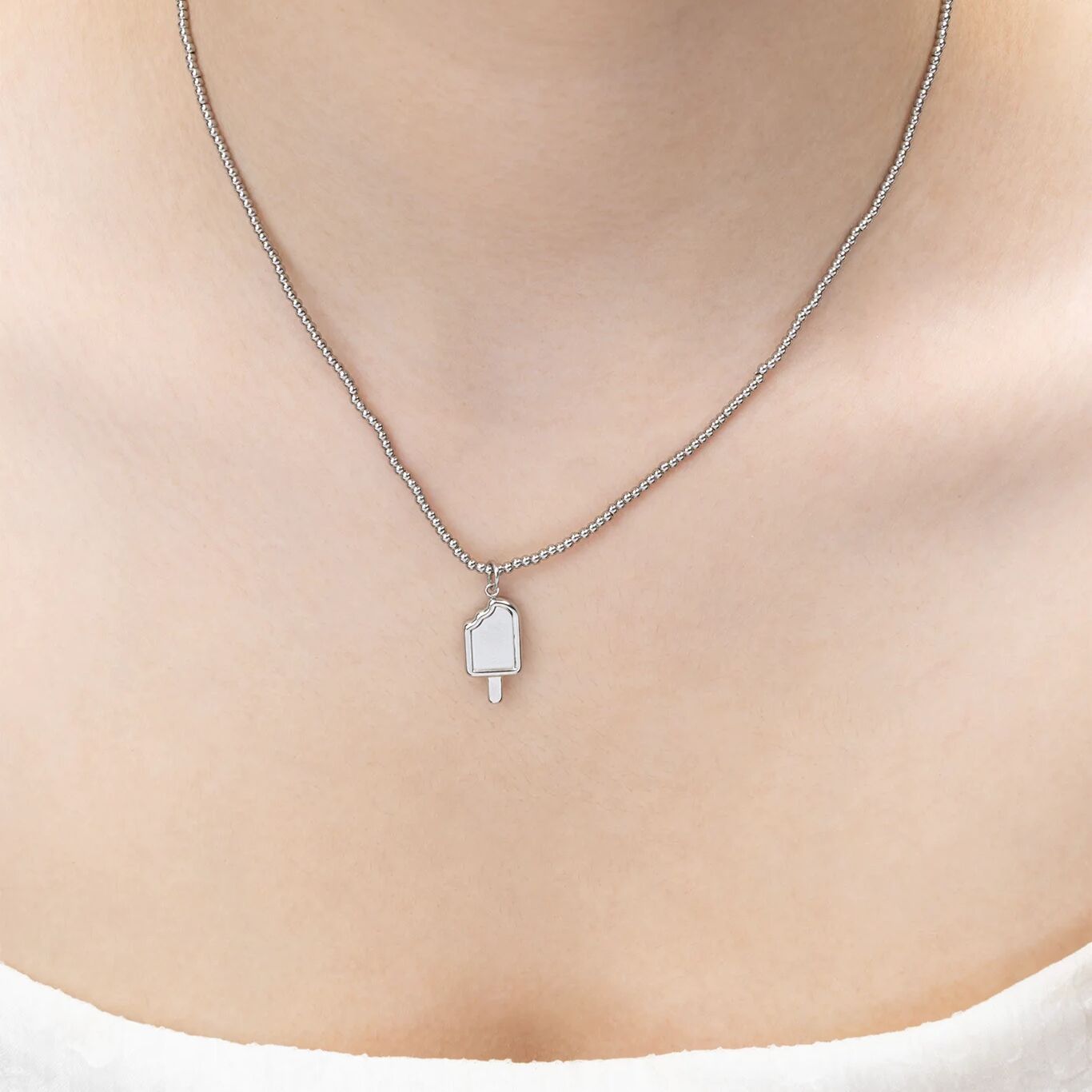 Silver necklace with a pendant on a person's neck