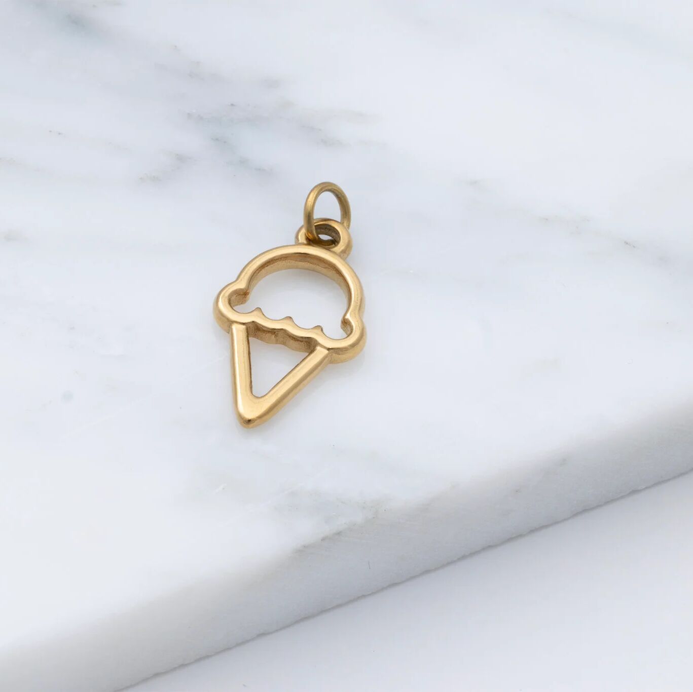 Gold ice cream cone pendant on a marble surface