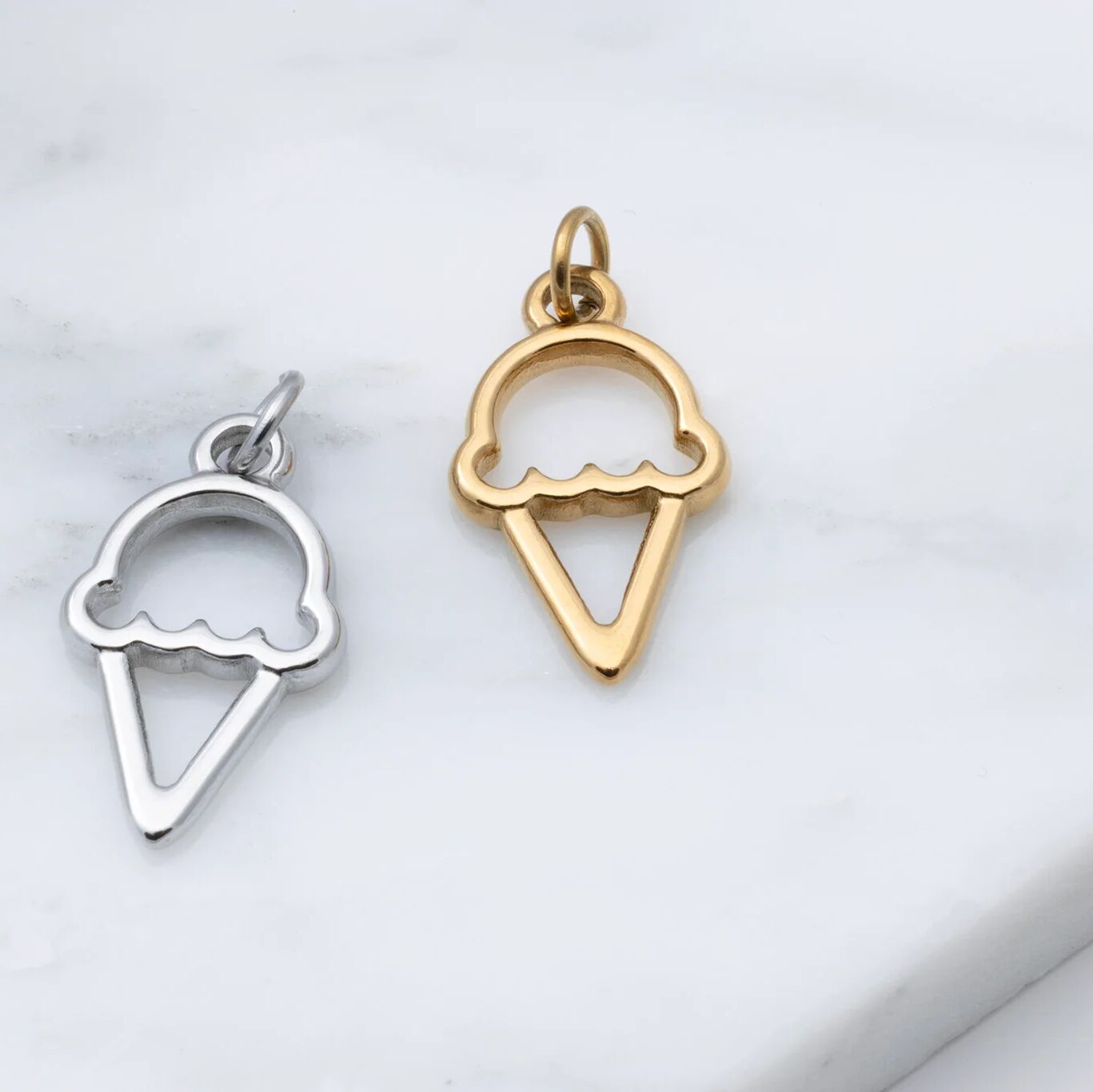 Gold and silver ice cream cone pendants on a light gray background