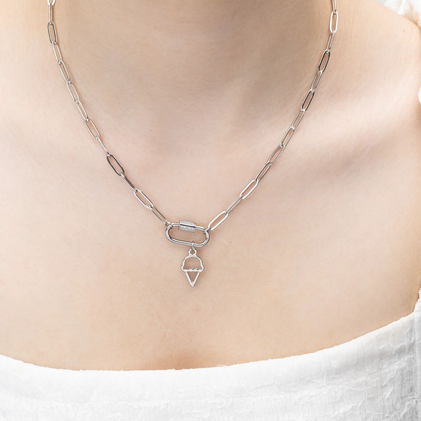 Silver chain necklace with a ice cream pendant on a person wearing a white top.