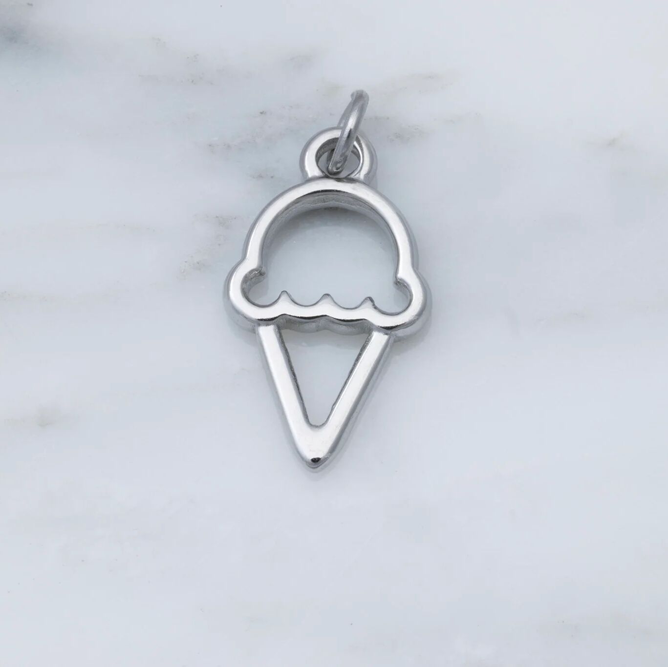Silver ice cream cone pendant on a marble background