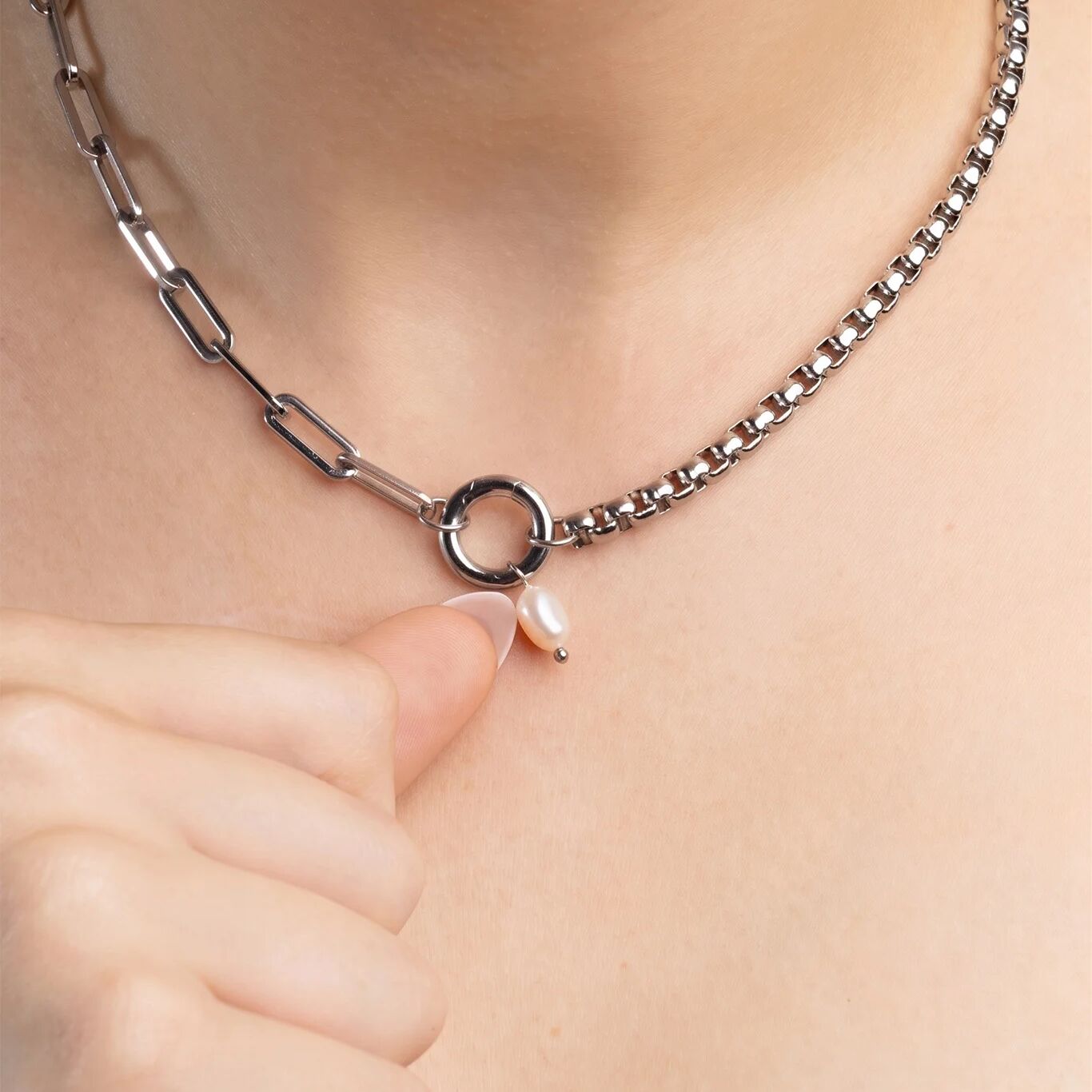 Silver chain necklace with a pearl pendant on a person's neck
