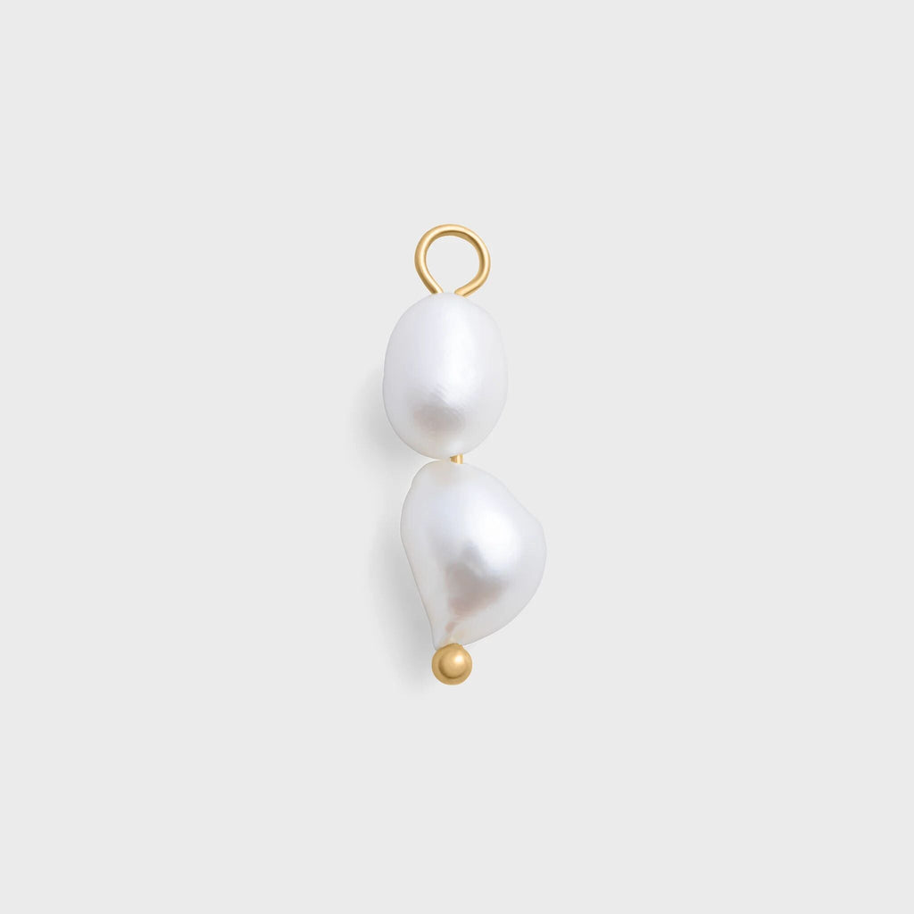 Pearl charm with gold hook on a light gray background