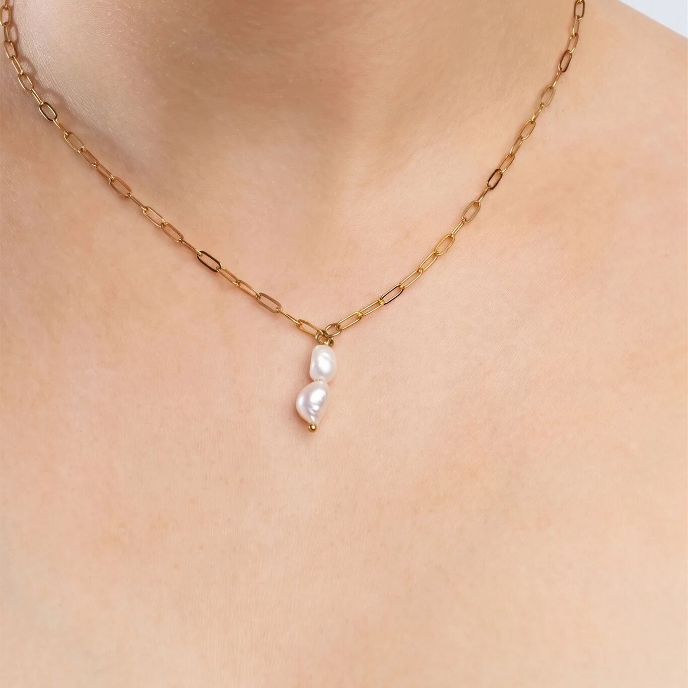 Gold chain necklace with pearl pendants on a person's neck