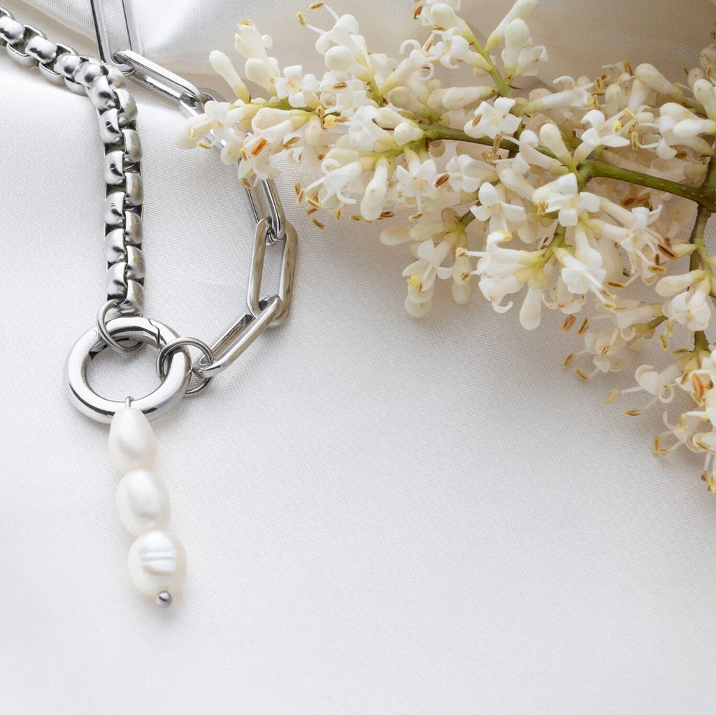 Silver bracelet with pearl charm and white flowers on a light background