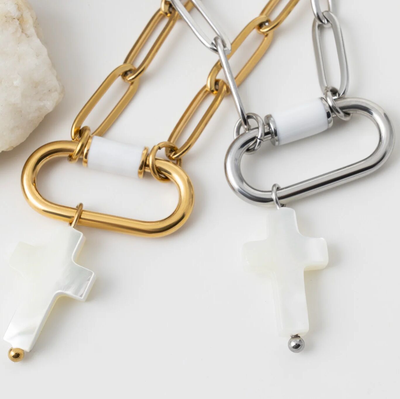 Two chain necklaces with cross-shaped pendants on a light background