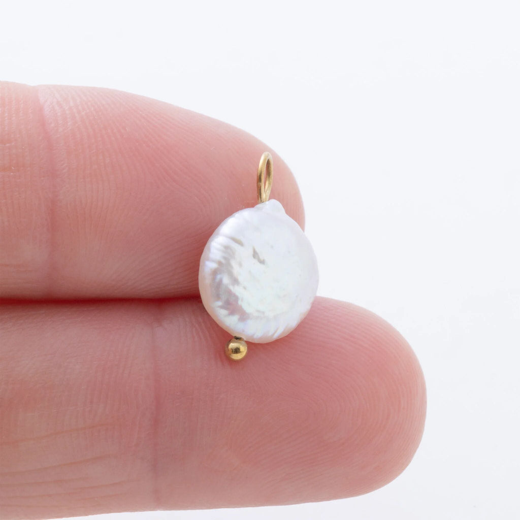 Pearl earring on a finger with a plain background