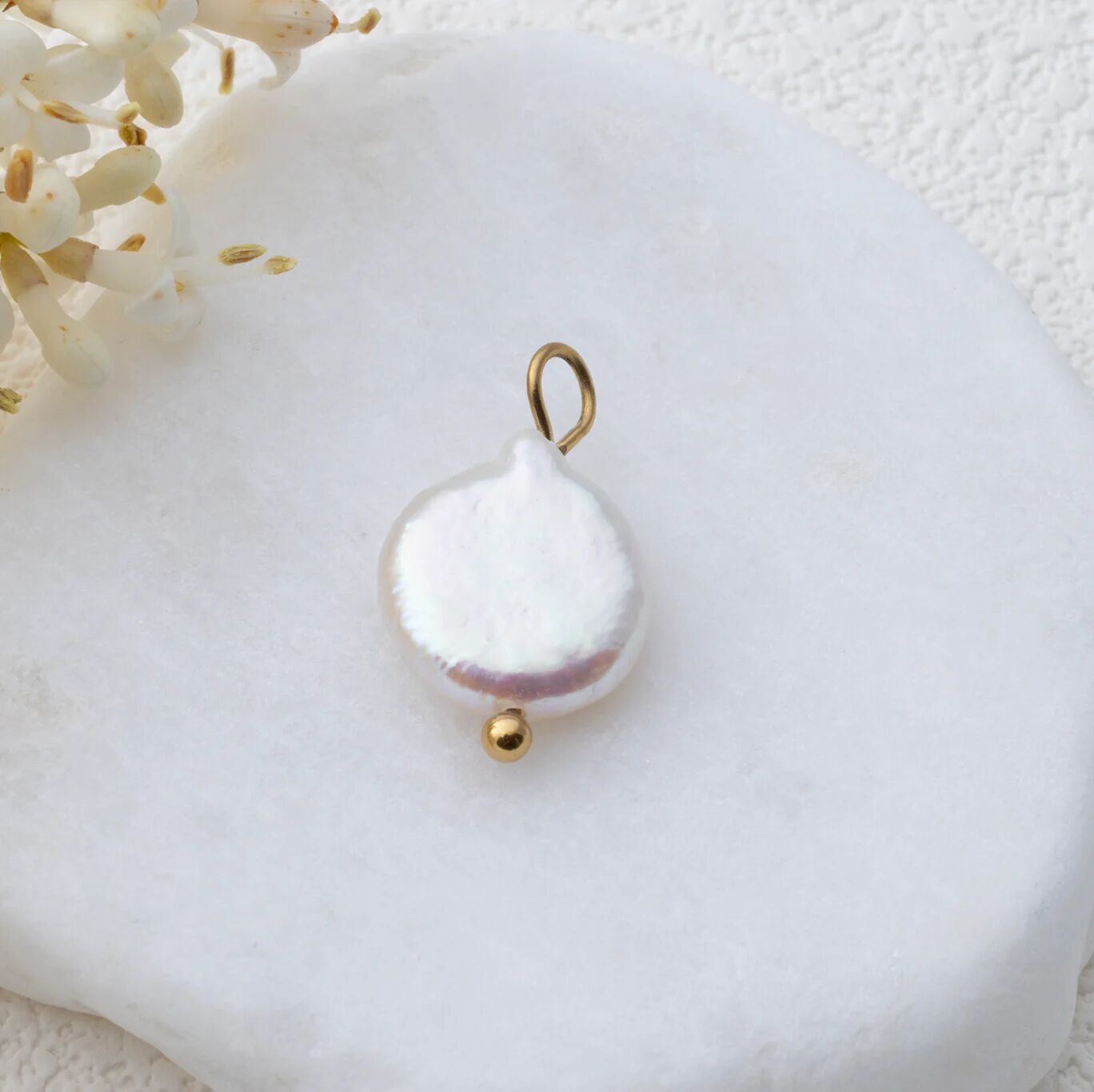 Pearl pendant with gold accents on a white background
