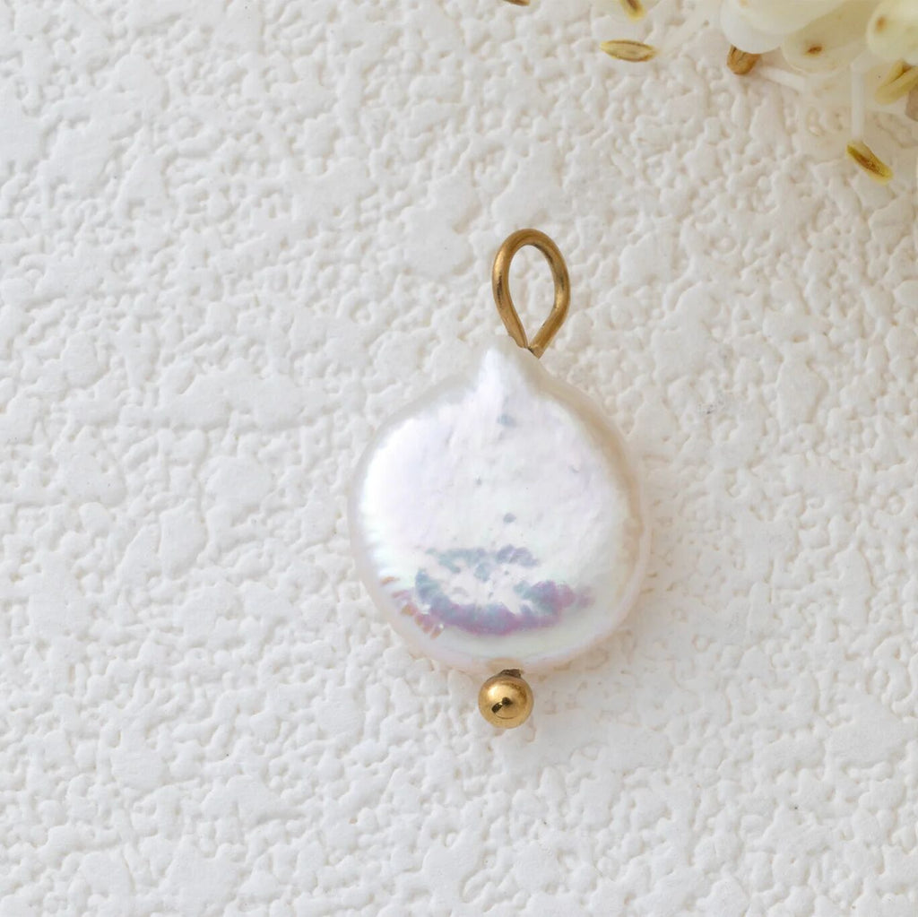 Pearl pendant with gold accent on a textured white background