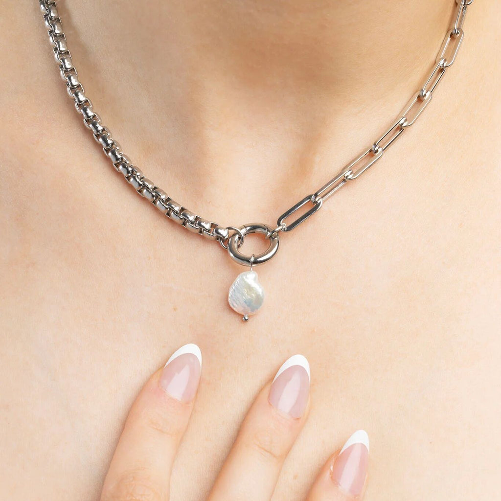 Silver chain necklace with a pearl pendant on a person's neck