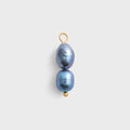 Two black pearls on a gold hook against a light gray background