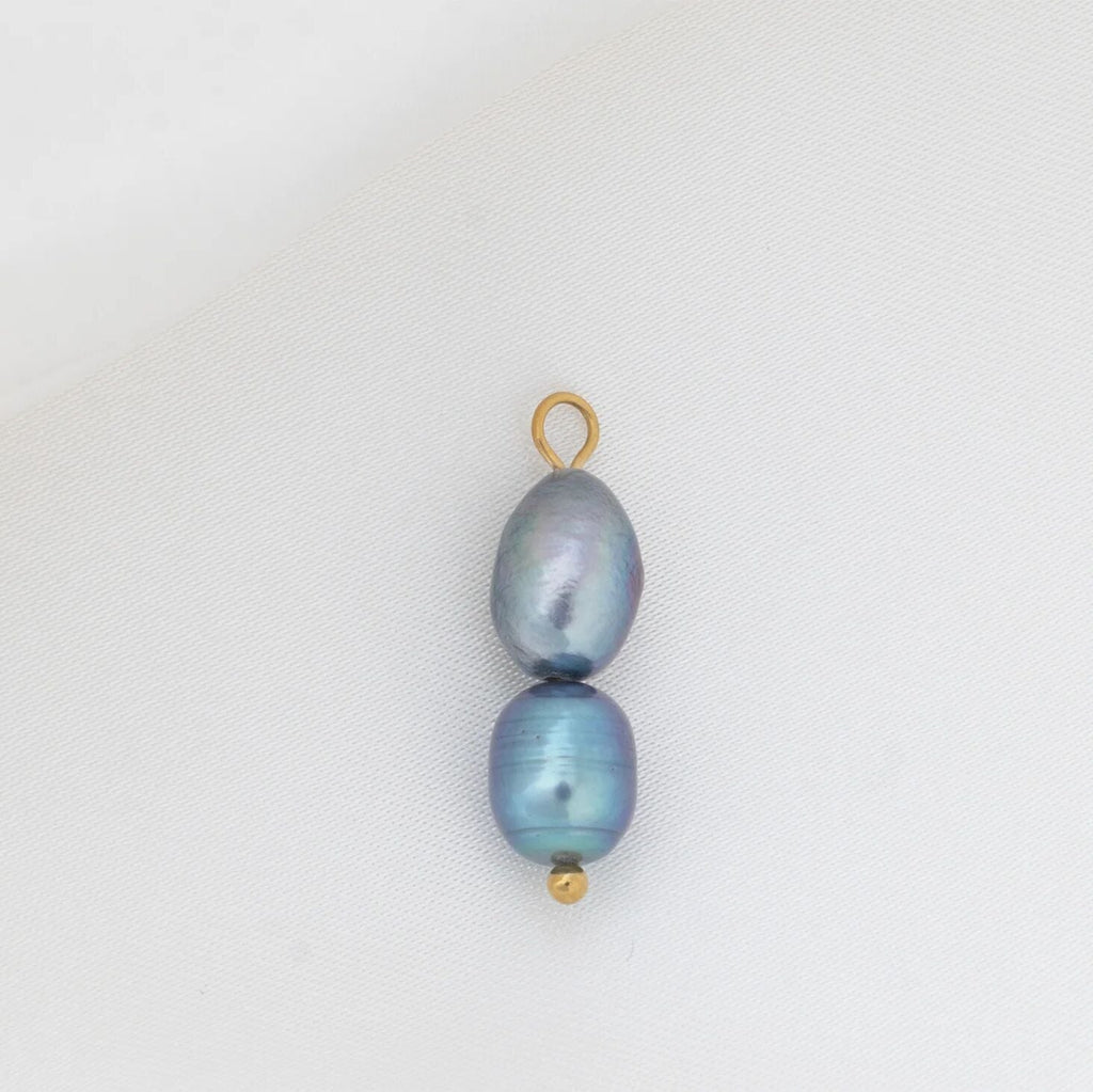 Two black pearls with gold clasps on a white background