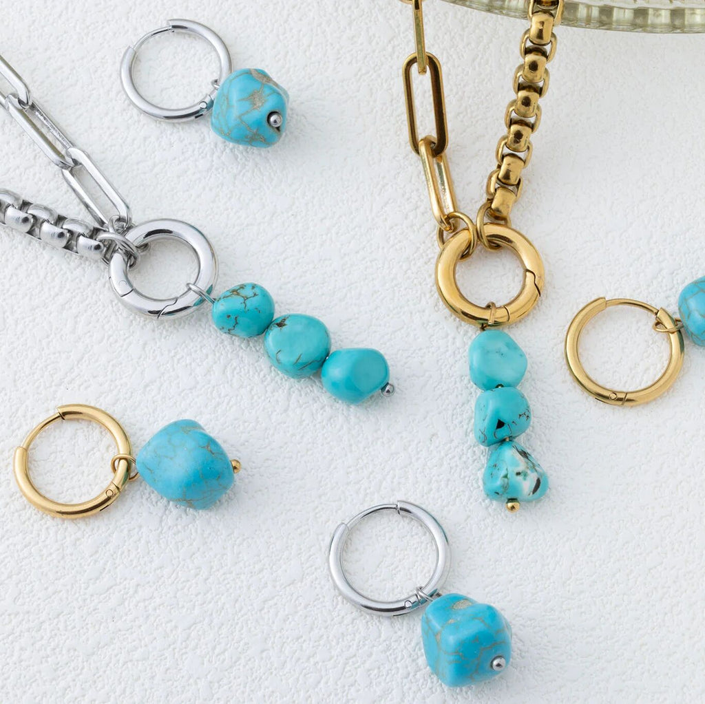 Jewelry set with turquoise beads and gold and silver chains on a white background