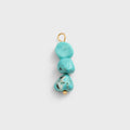 Turquoise stone pendant with gold accents on a light gray background