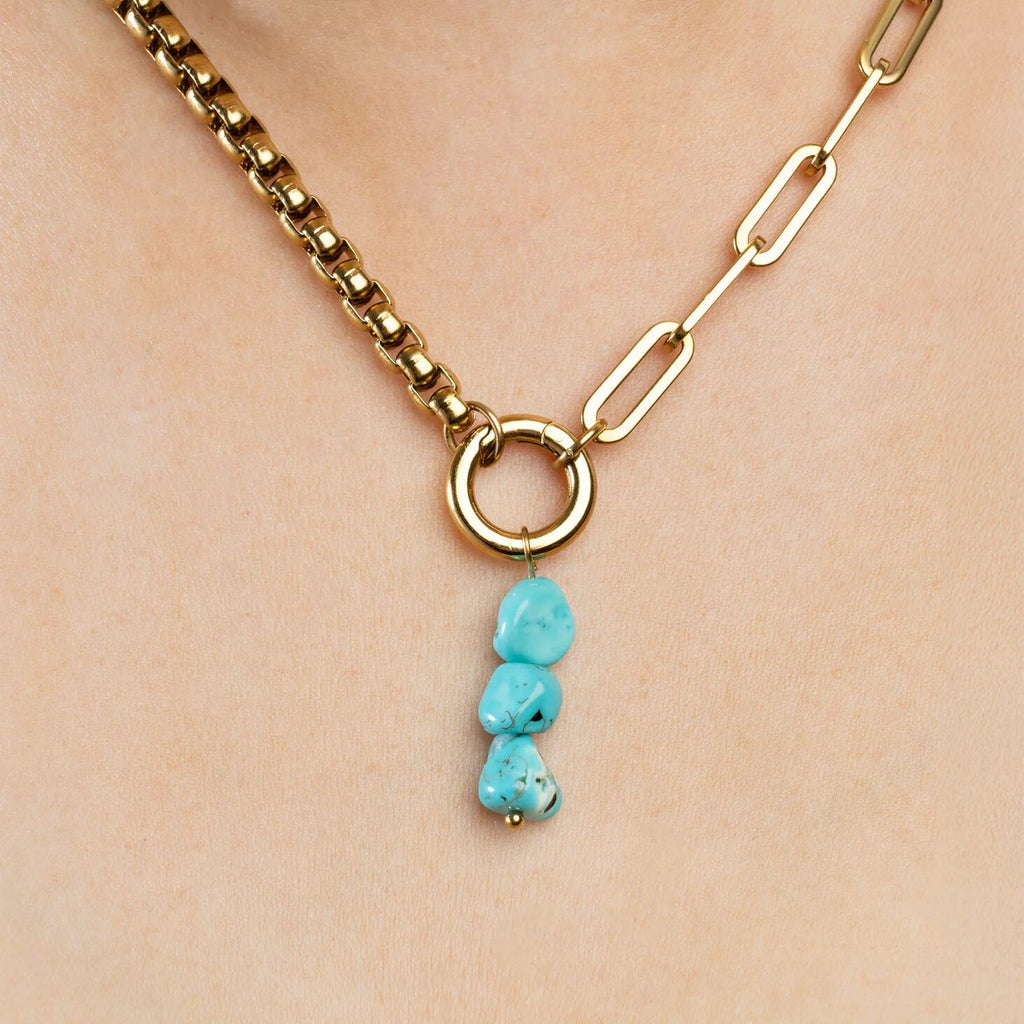Gold necklace with turquoise pendant on a beige background