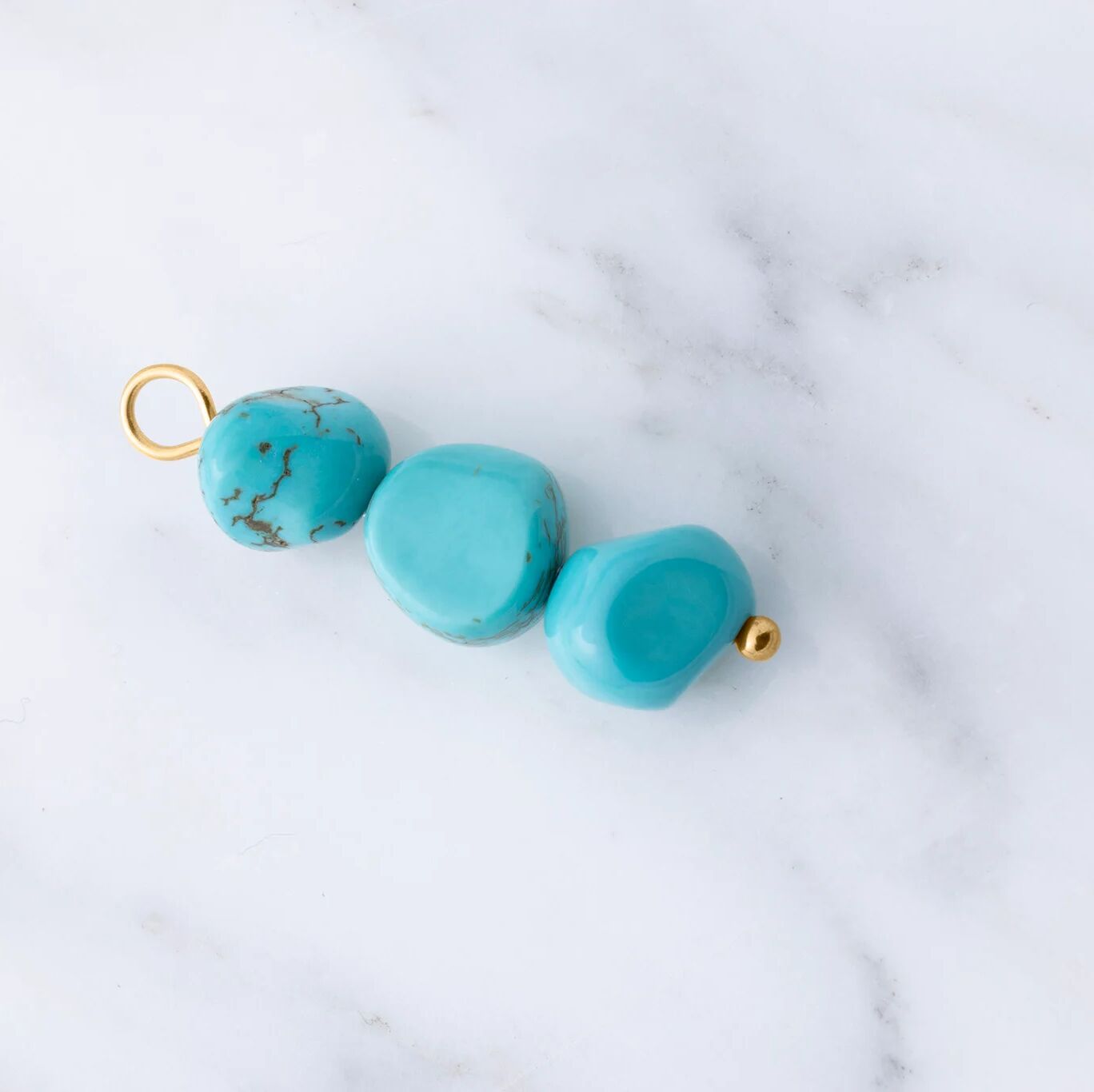 Turquoise beads with gold accents on a marble surface