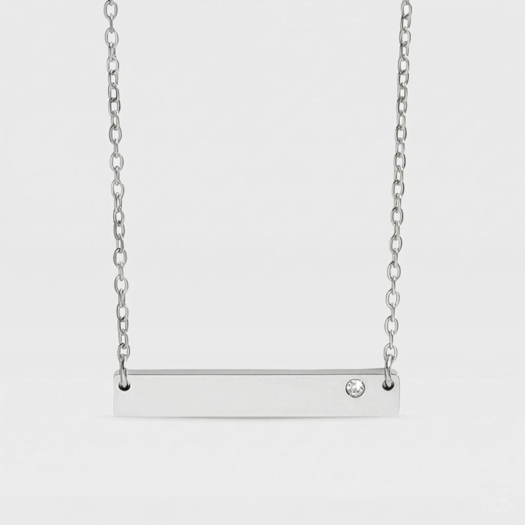 Silver bar necklace with a small diamond on a light gray background
