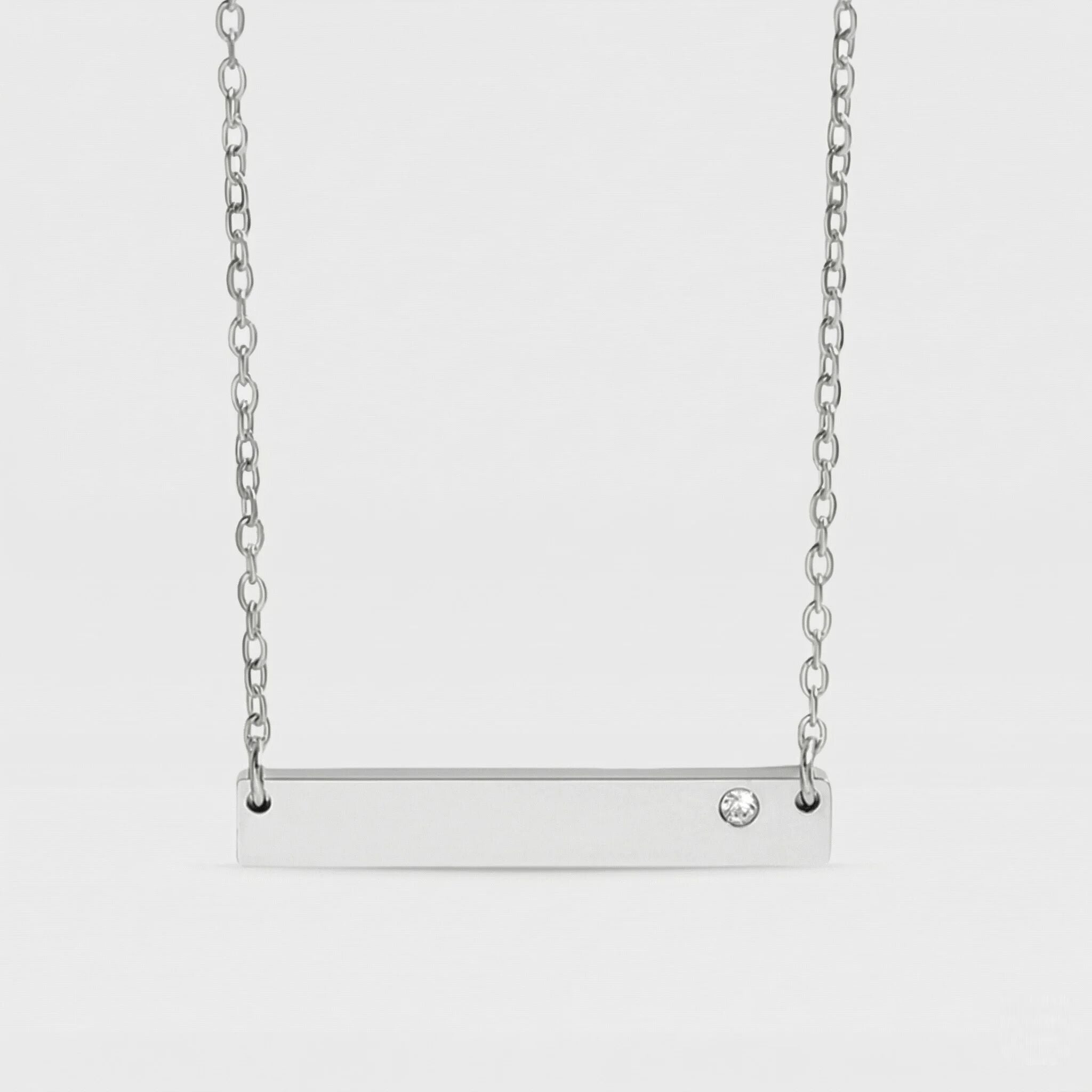 Silver bar necklace with a small diamond on a light gray background