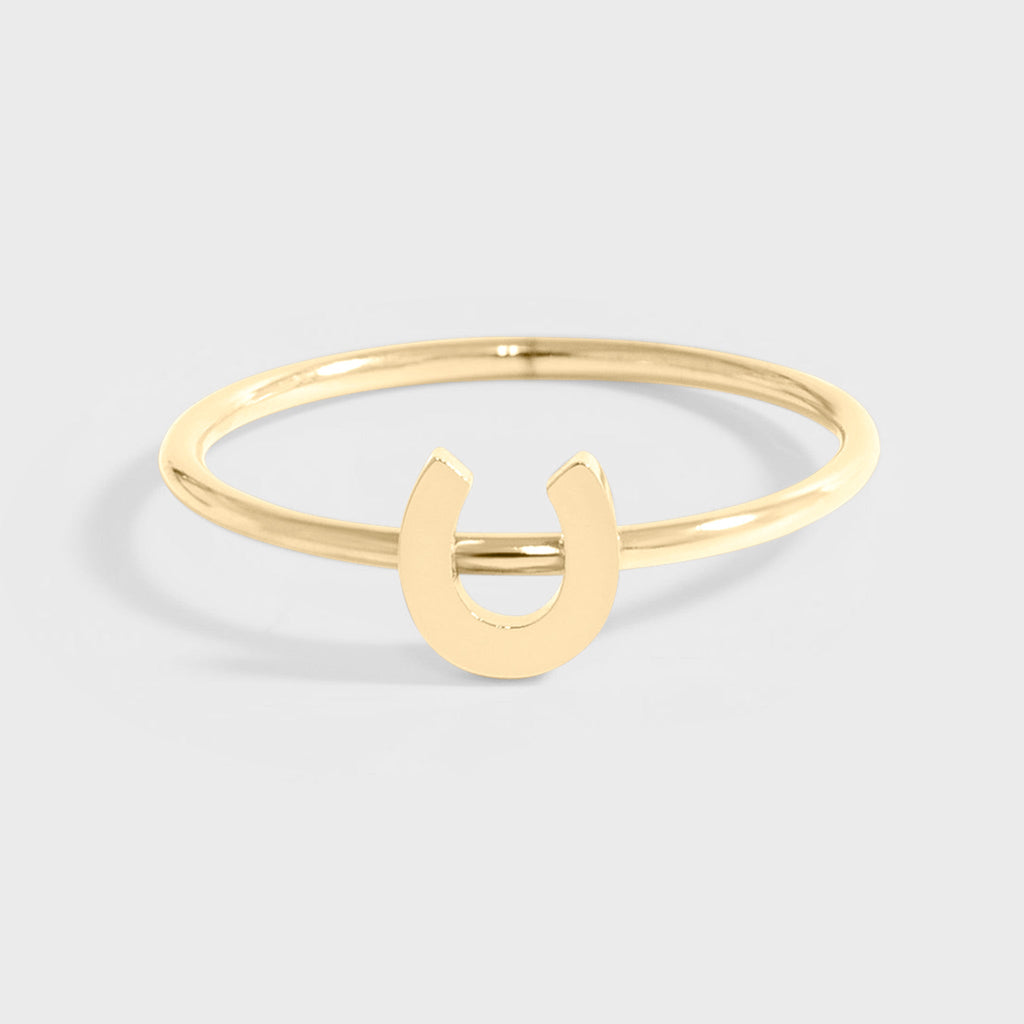 A gold-colored horseshoe ring on a white background