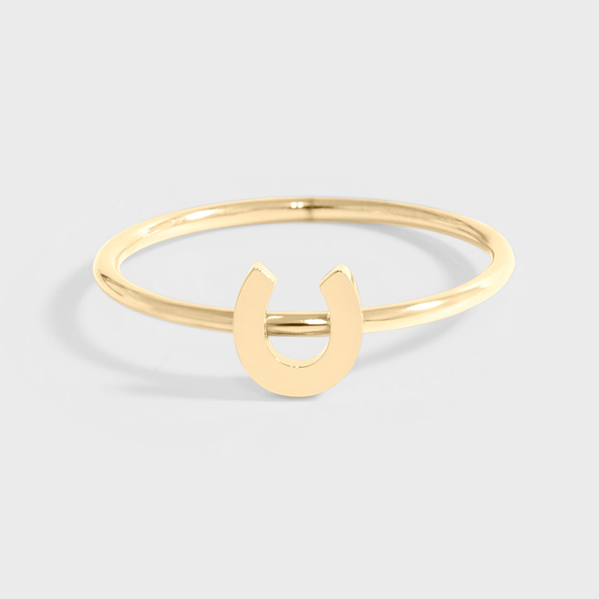 A gold-colored horseshoe ring on a white background