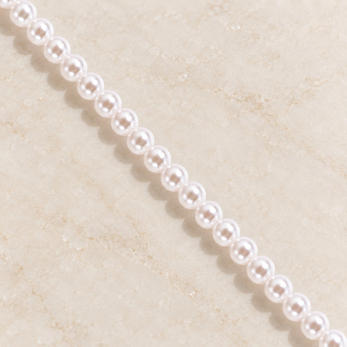 Iris Pearl Strand — round white pearl detail on ivory stone; AI-generated supporting image.