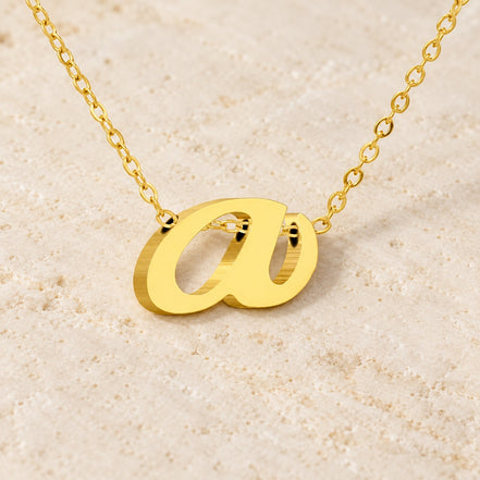 Luna Initial Necklace — gold lowercase A variant on ivory stone; AI-generated supporting presentation.