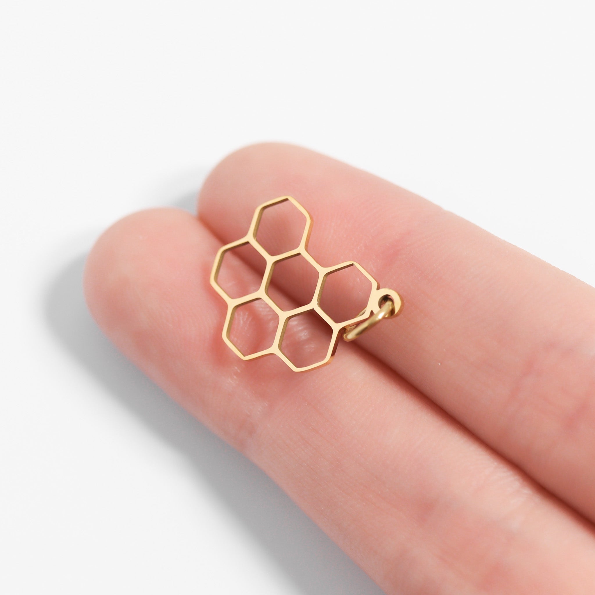 Gold honeycomb pendant against two fingers