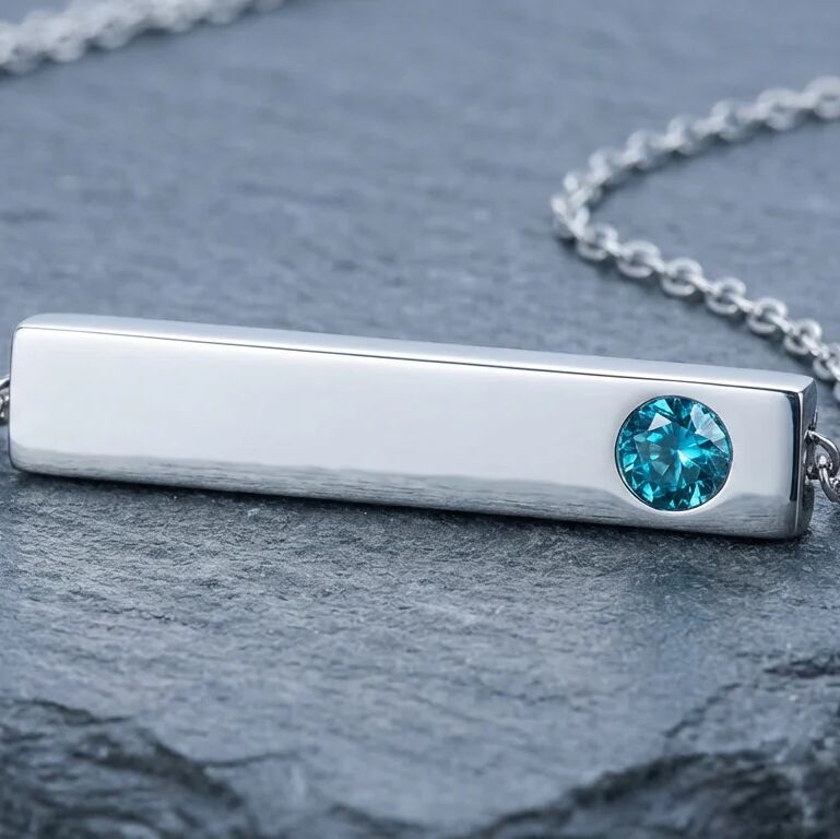 Silver bar necklace with a blue gemstone on a dark surface
