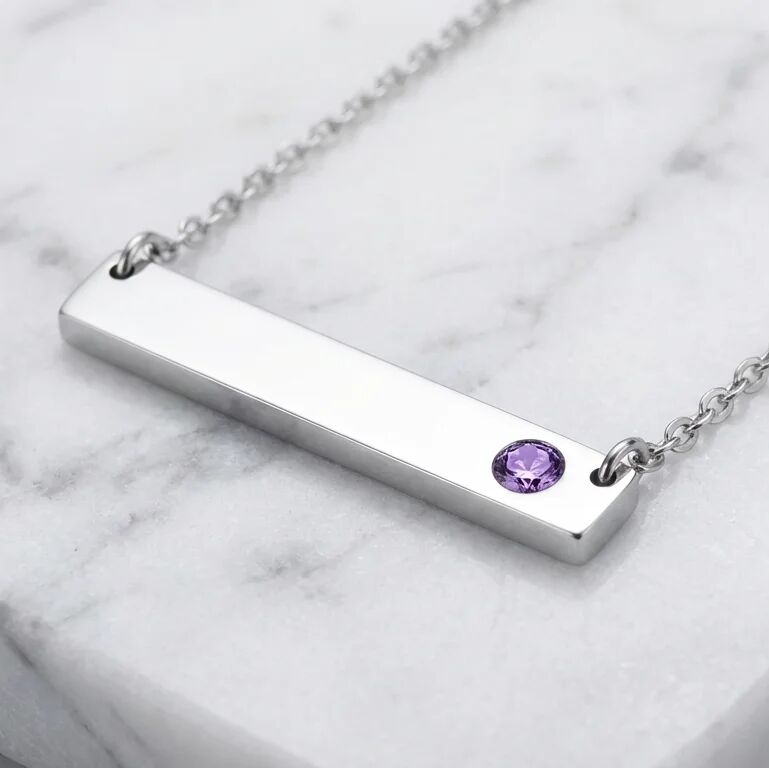 Silver bar necklace with a purple gemstone on a marble background